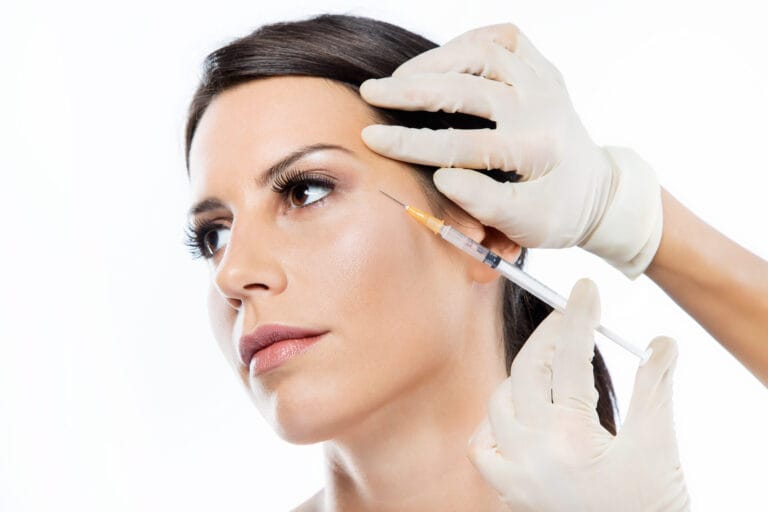 Beautiful young woman getting botox cosmetic injection in her fa Image description