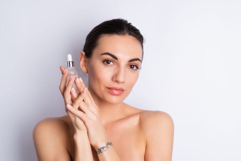 Close beauty portrait of topless woman with perfect skin and natural make-up, holds serum for youth and skin hydration, dropper with cosmetic oil Image description